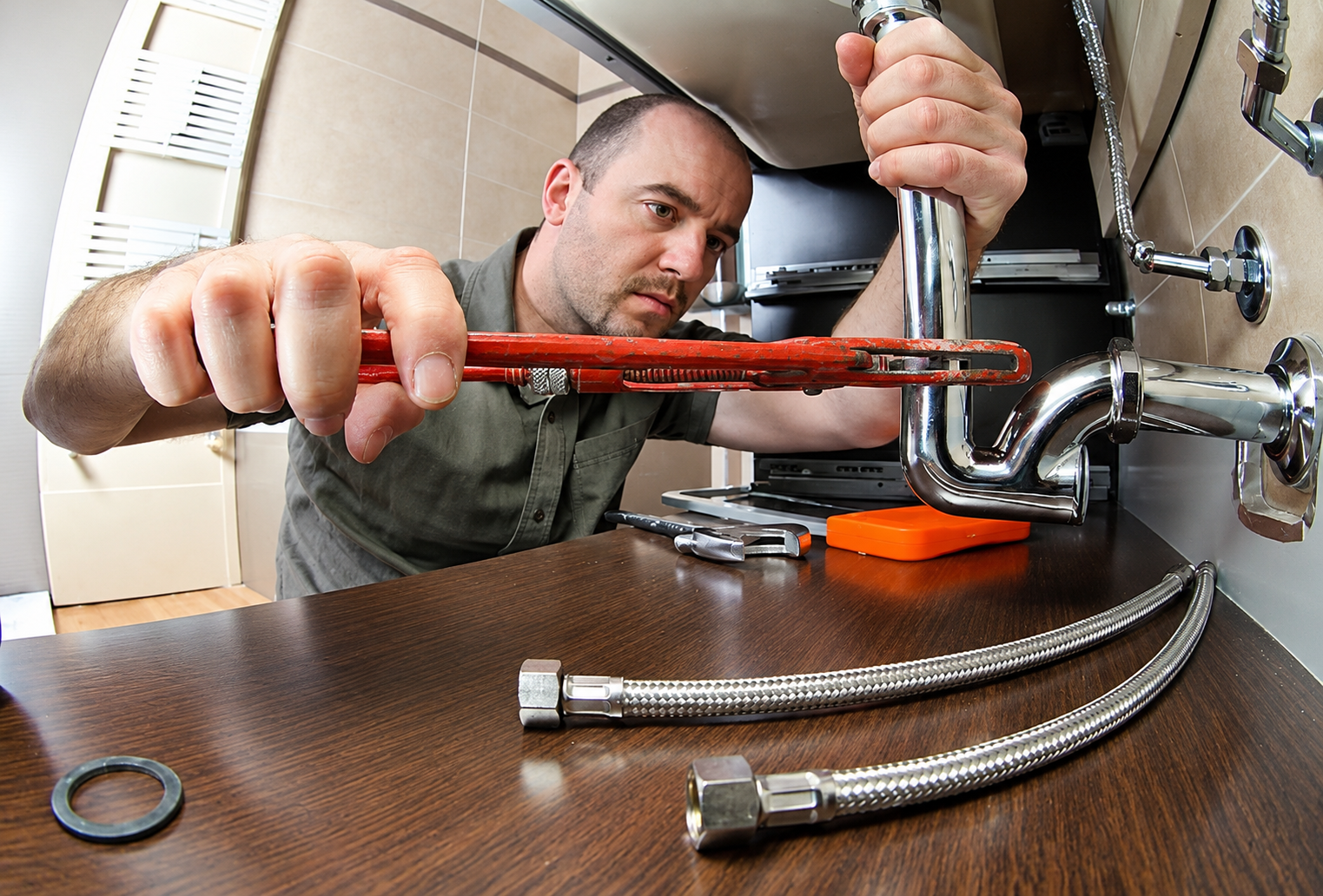 Plumber repairing pipes beneath a sink